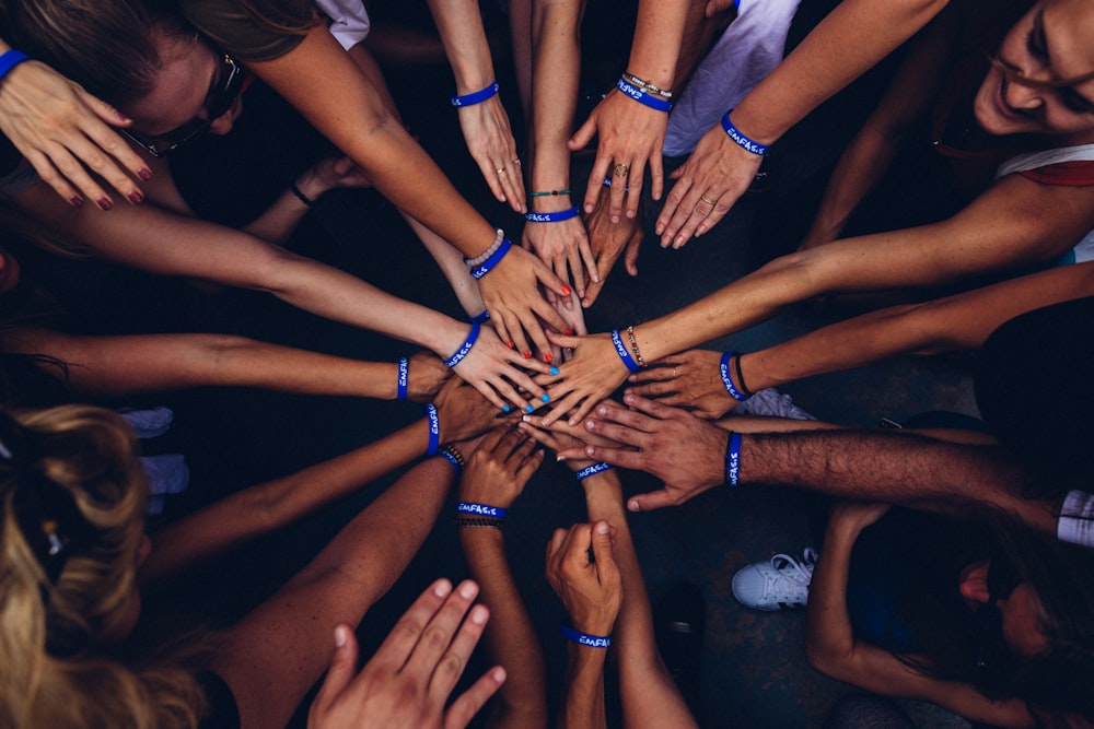 Many hands joined together in the centre, symbolising unity and women-led community empowerment